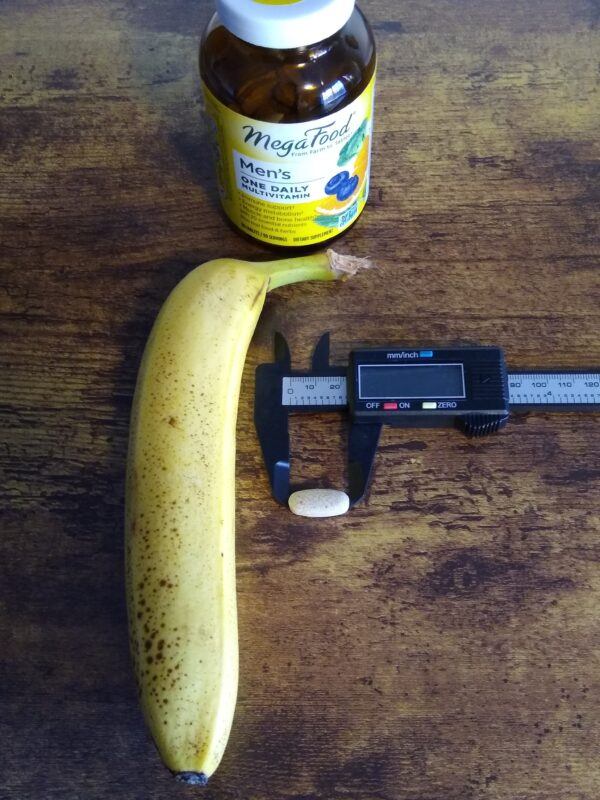 Megafood Men's One Daily Multivitamin measurement and banana for scale